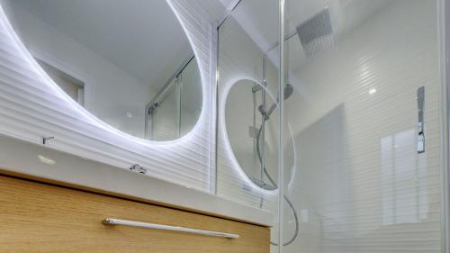 a bathroom with a shower with a round mirror at Le Brière - Appart'Escale in Saint-Nazaire