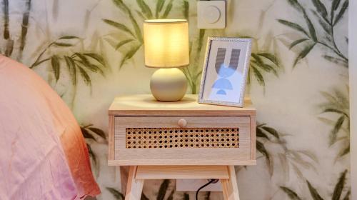 a nightstand with a lamp and a picture on it at Le Brière - Appart'Escale in Saint-Nazaire