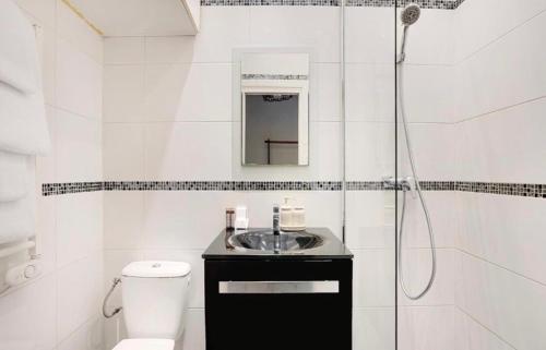 une salle de bain blanche avec un lavabo et une douche dans l'établissement Charmant studio au cœur de paris, à Paris