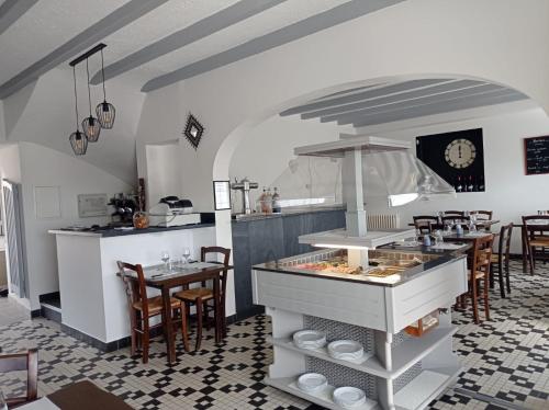 une cuisine avec un comptoir et une table avec des chaises dans l'établissement Auberge Armoricaine, à Louisfert