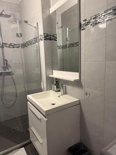 une salle de bain blanche avec un lavabo et une douche dans l'établissement Bas de Villa à 15 min de Nice avec piscine, à Carros