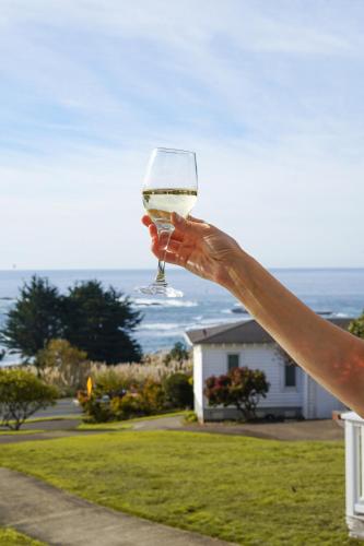 a person holding up a glass of white wine at Little River Inn in Little River