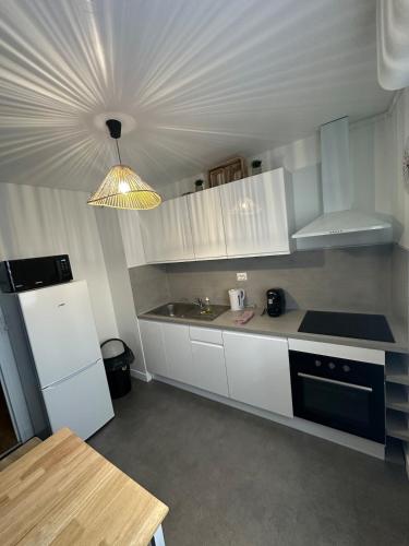 une cuisine avec des armoires blanches et un meuble lumineux dans l'établissement Au calme, à Saint-Brieuc