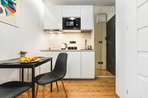 a kitchen with white cabinets and a table and chairs at Stylowe Apartamenty w Centrum in Wrocław