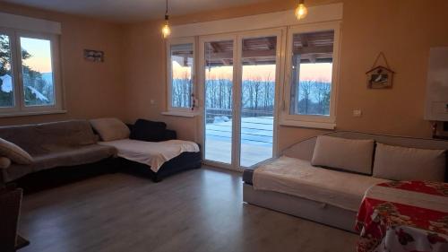 a living room with a couch and a bed and windows at Villa Sunset in Banja Luka