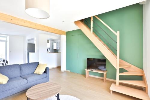 - un salon avec un canapé bleu et un escalier dans l'établissement Le Cocon Vert des Vosges, à Munster