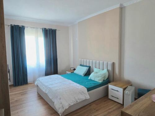 a bedroom with a bed with blue sheets and a window at Dragos Nest Center in Kamëz