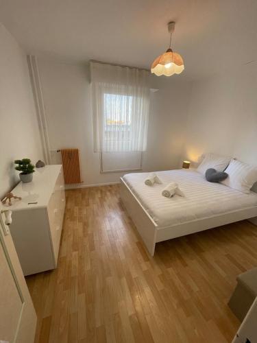 une chambre avec un lit blanc et un parquet dans l'établissement Appartement bambou, à Vandœuvre-lès-Nancy