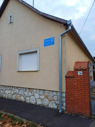 a house with a blue sign on the side of it at Vendégház in Udvar
