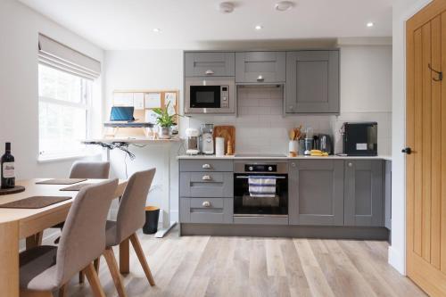 a kitchen with gray cabinets and a table with chairs at Rock Mill Retreat in Stony Middleton