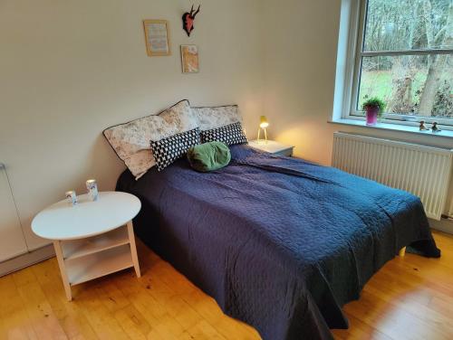 a bedroom with a bed and a table and a window at Guest house on farm in small village in Næstved