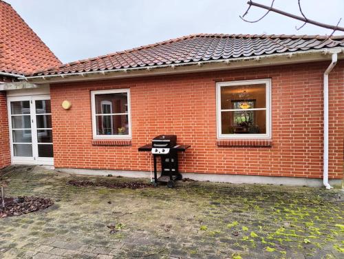 a brick house with a grill in front of it at Guest house on farm in small village in Næstved