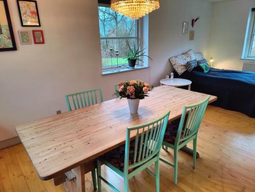 a wooden table with chairs and a vase of flowers on it at Guest house on farm in small village in Næstved