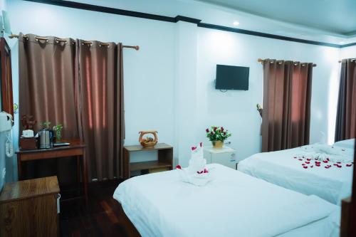 a hotel room with two beds and a television at Vientiane Ruby Riverside Hotel in Vientiane