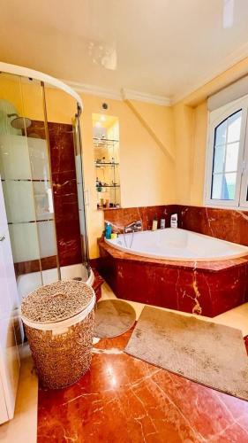 une grande salle de bain avec baignoire et douche dans l'établissement Maison spacieuse à Chelles, à Chelles
