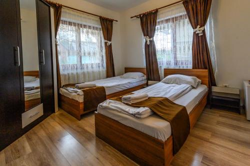a bedroom with two twin beds and a television at Pensiunea Crinul Alb in Deseşti