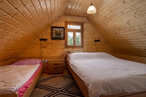 two beds in a wooden room with a window at Mountain Hut Stara Hiša in Kupjak