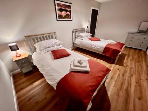 a bedroom with two beds with red and white sheets at Luxury 3 Bedroom House - Stag Moor House in Portree