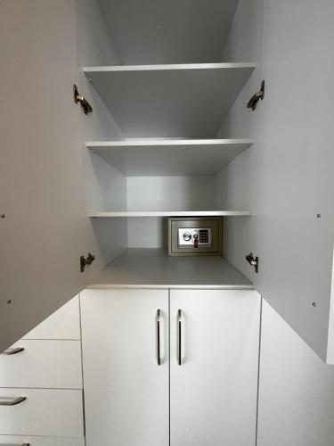 a white kitchen with white shelves and a microwave at Su Apartment Side in Side