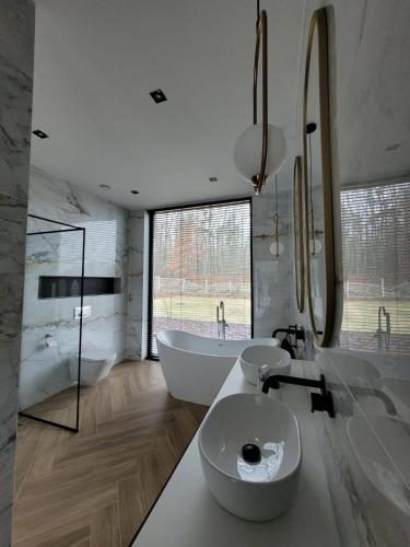 a bathroom with two sinks and a bath tub and a tubermott at Ostatni dom po lewej in Białe Błoto