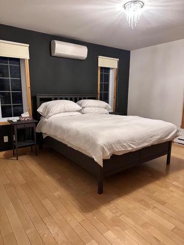 a large bed in a bedroom with a black wall at Le Grand Boisé in Saint Zenon