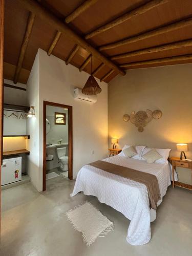 um quarto com uma cama grande e um banheiro em Pousada Amora Caraiva em Caraíva