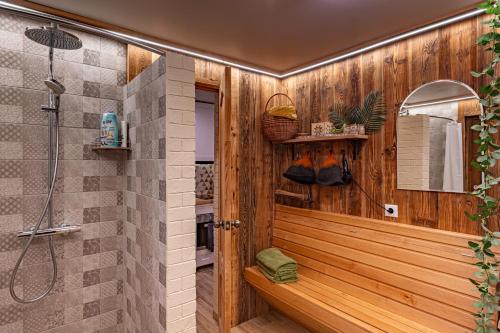 a bathroom with a shower and a wooden wall at Mīļpirtiņa Guguči in Straupe