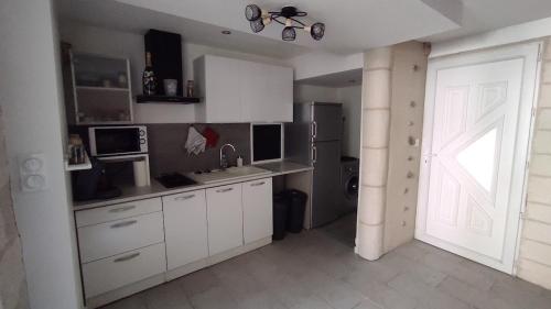 a kitchen with white cabinets and a door and a refrigerator at Appartement cosy avec terrasse in Sainte-Foy-la-Grande