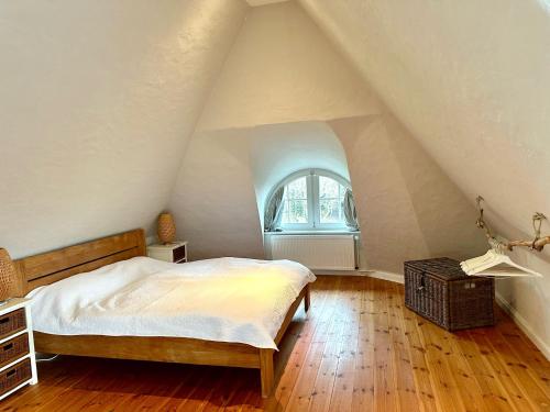 Grubeにある1100 - Reetdachhaus in Grubeのベッドと屋根裏部屋の窓がある屋根裏部屋の寝室