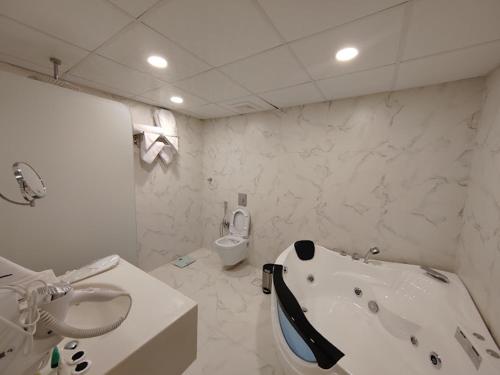 a bathroom with a tub and a sink and a toilet at نورس الشمال للشقق المخدومة in Umm Lujj