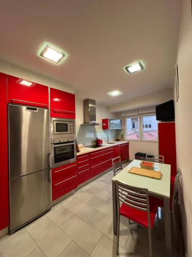 a kitchen with red cabinets and a table and a refrigerator at Marusía apartamento in Malpica