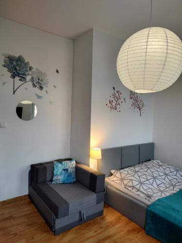a bedroom with a bed and a couch and a chandelier at Benny 3 na wyłączność in Toruń