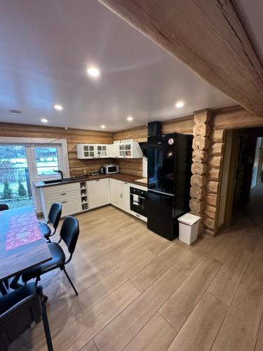 a kitchen with white cabinets and a black refrigerator at Villa Rose & SPA in Mežciems