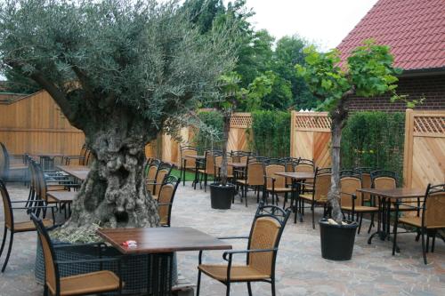 a patio with tables and chairs and a tree at Landgasthaus Hotel Wolters in Kerken