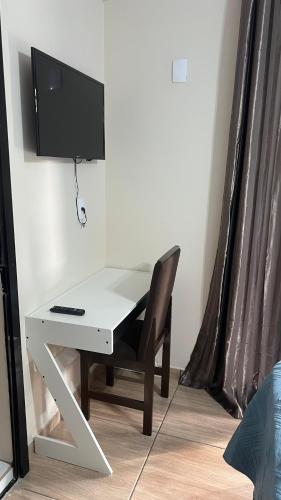 a white desk with a computer and a chair at Quarto Aconchegante N 2 in Rio Negro