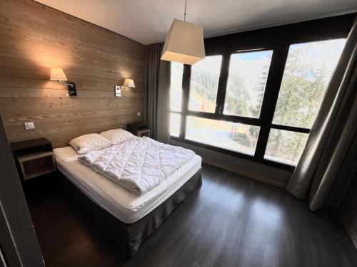 a bedroom with a bed and a large window at Résidence Le Panoramic - Appartement lumineux · Départ et retour skis aux pieds · Piscine · Parking inclus · Spa MAE-0351 in Magland