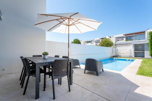 a patio with a table and chairs and an umbrella at Villa Oliveira in Sesimbra