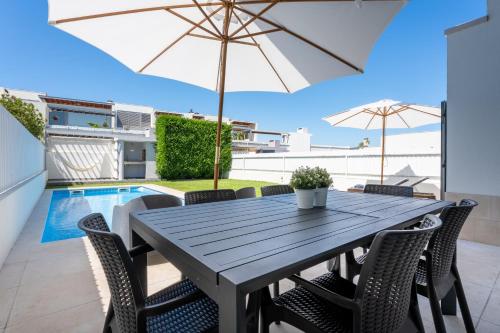 a dining table with chairs and an umbrella on a patio at Villa Oliveira in Sesimbra