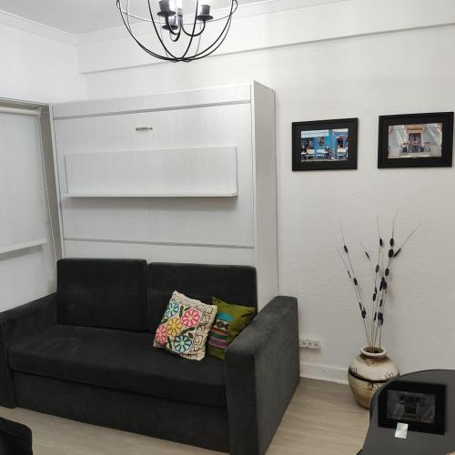 Estilo Mar في مار ديل بلاتا: أريكة سوداء في غرفة معيشة مع ثريا