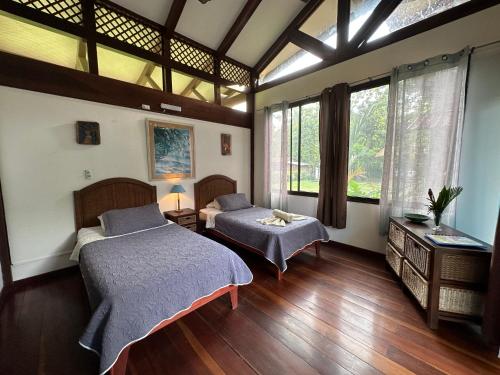 カウイータにあるHotel Kenaki Lodgeのベッドが2つと大きな窓がある寝室