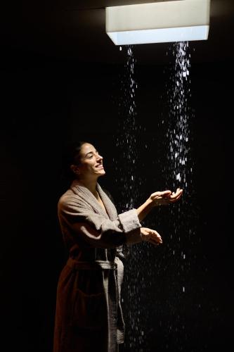a woman standing under a light with water pouring out at Hotel Cesa Tyrol in Canazei