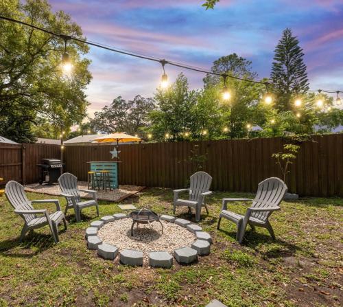 a backyard with chairs and a fire pit with an umbrella at Beach Life at Clearwater 10 minutes from the beach in Clearwater