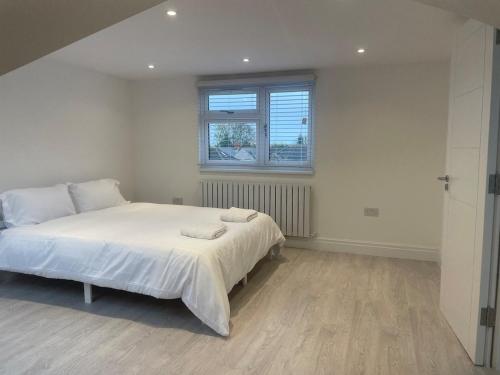 Un dormitorio blanco con una cama y una ventana. en 5 Bedroom Modern and Spacious House in London, en Fairlop Station