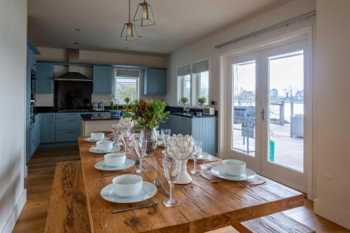 a kitchen with a wooden table with plates and wine glasses at Summer Lake in South Cerney