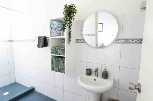 a white bathroom with a sink and a mirror at Botanical Apartment Central Boho style 2 pools in Willemstad