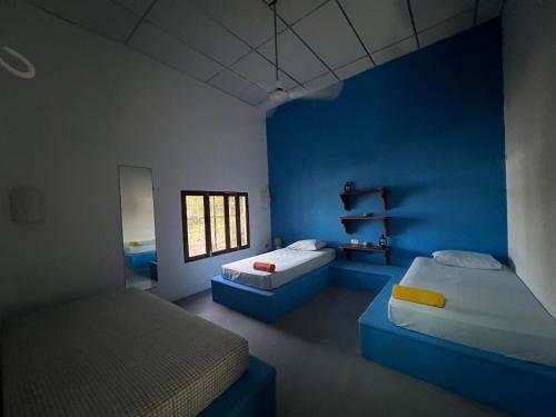 a room with two beds and a blue wall at Buena Onda Backpackers in San Juan del Sur