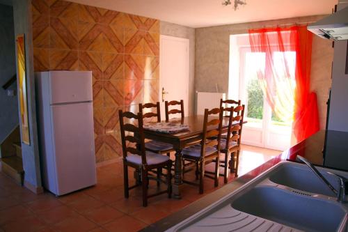 a kitchen with a table and chairs and a refrigerator at Gite FABYPHIL in Youx