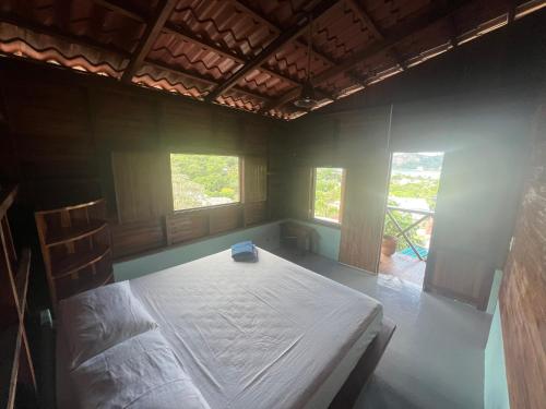 a bedroom with a bed in a room with two windows at Buena Onda Backpackers in San Juan del Sur