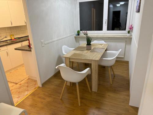 a small kitchen with a wooden table and white chairs at Skyline Retreat Jedes Zimmer mit TV in Baden