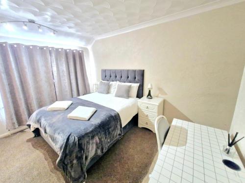 a bedroom with a bed and a table and a window at Cosy Luxurious Large 3 bedroom house, free parking, free WiFi in Havering atte Bower